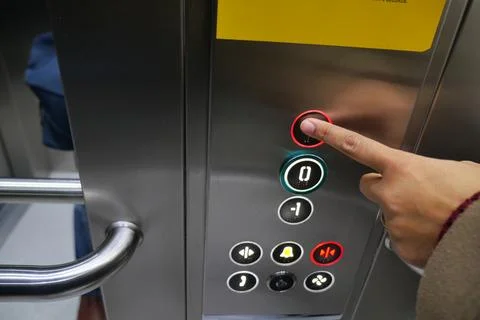 Finger pressing elevator button in building hallway Stock Photos