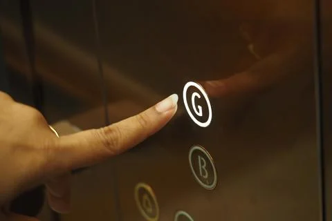 Finger pressing the elevator button for ground floor access Foto stock