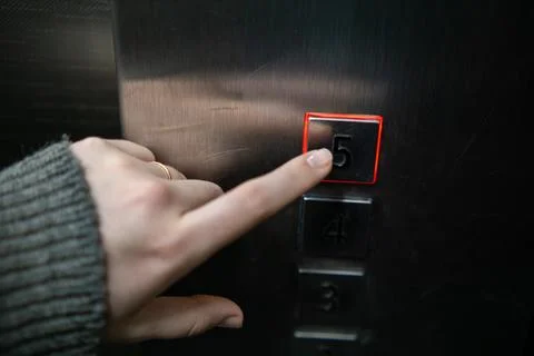 Finger pressing elevator button number five. Stock Photos