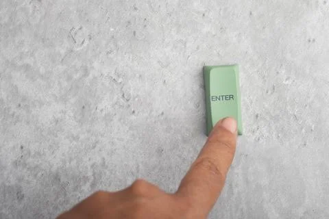 Finger pressing Enter button on gray background.Copy space. Stock Photos