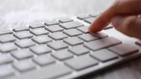 Finger pressing an enter key. Computer user hitting the enter key, up close Stock Photos