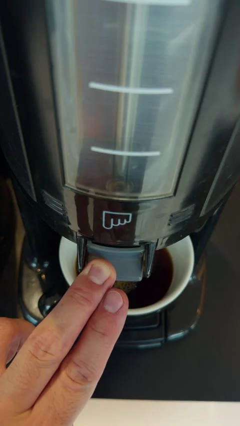 Finger pressing espresso machine button as coffee pours into cup in modern Stock Footage 345530555