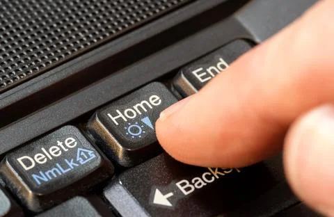 Finger pressing a home button on a simple laptop computer keyboard, object .. Foto stock