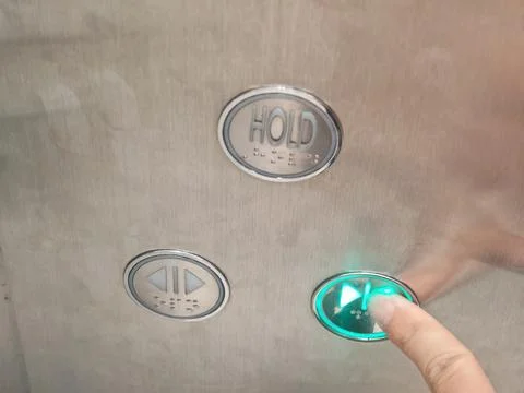 Finger Pressing Illuminated Green Elevator Door Close Button with Braille Stock Photos