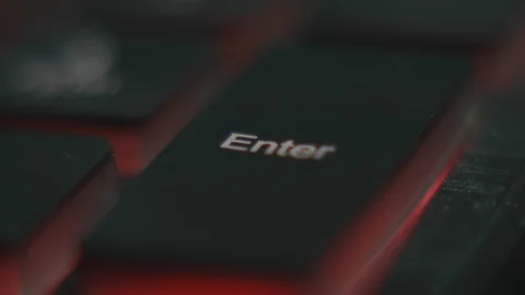 Finger pressing the key Enter on a computer keyboard. English keyboard with red Stock Footage 105653612