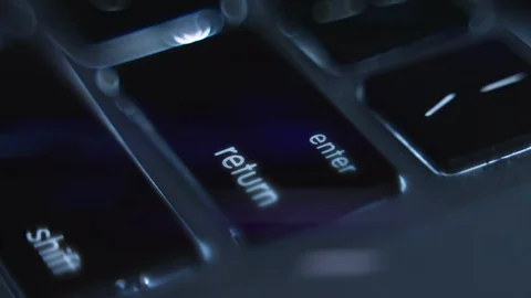 Finger pressing the key Enter on a computer keyboard. English keyboard with blue Stock Footage 105654641
