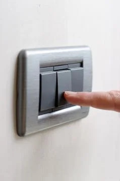 Finger pressing light switch, turning it on or off Stock Photos