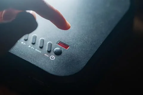 Finger pressing power button on electronic device Stock Photos