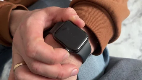 Finger pressing power button on smartwatch to turn it on, wearable technology Stock Footage 337120243