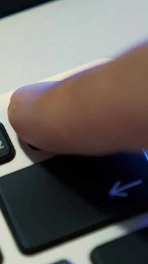 Finger is pressing power button to turn on laptop, close up. Vertical video Stock Footage 317304920