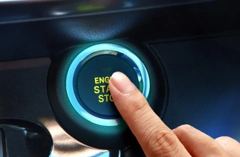 Finger pressing the start or stop engine button in close up. Stock Photos