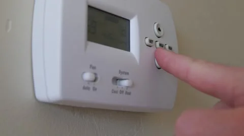 A finger programs the thermostat in a home Stock Footage 46572978