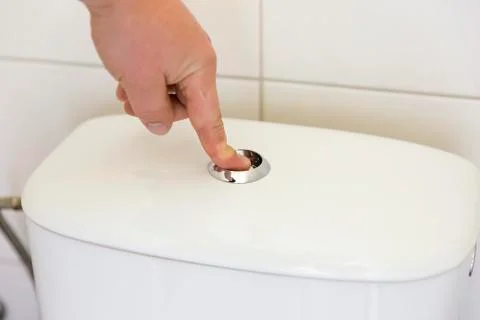 Finger pushing button and flushing toilet. Stock Photos