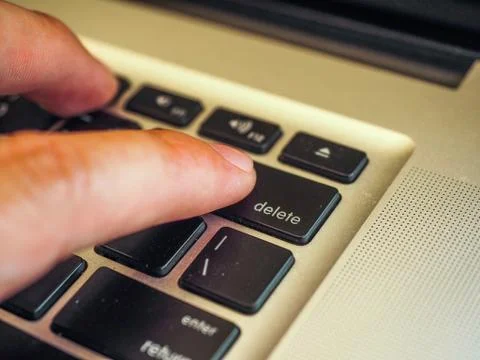 Finger pushing delete button on a keyboard of computer Stock Photos
