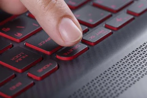 Finger pushing delete button on laptop keyboard Stock Photos