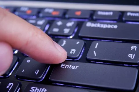 A finger is pushing the enter button Stock Photos