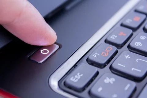 A finger is pushing the power button to wake laptop up Stock Photos