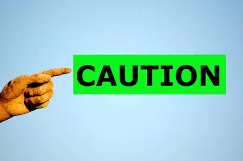 Finger with rectangular green label CAUTION Stock Photos