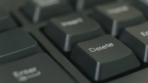 Finger repeatedly pressing the delete key on a black keyboard. Stock Footage 123951426