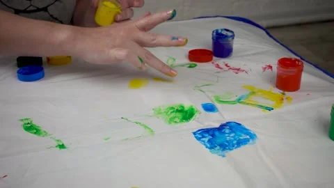 Finger safe childrens paints on the table and children's hands. An adult hand Stock Footage 171018117