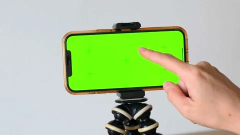 Finger swipes down green screen of smartphone, horizontally on tripod on white 스톡 동영상 220294483