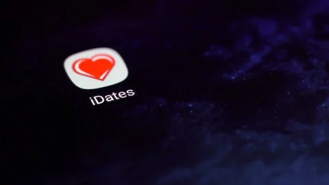 Finger tapping the iDates icon to open the application on a smartphone. Stock Footage 107167715