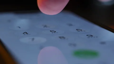 Finger tapping numbers to call on iPhone screen. Close up of iOS interface, user Stock Footage 334023023