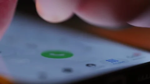 Finger tapping numbers to make a call on iPhone screen. Close up of iOS Stock Footage 334023034