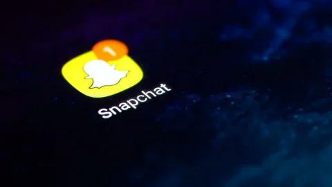 Finger tapping the Snapchat icon to open the application on a smartphone. Stock Footage 107168196