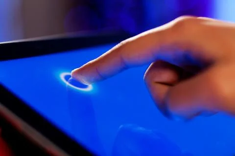 Finger Touching Blue Tablet Screen with Glowing Digital Interface Stock Photos