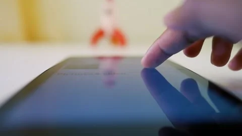 Finger Touching Tablet Screen with Rocket Toy in Background Stock Footage 317736802