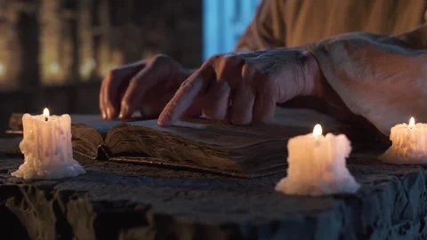 Finger tracing ancient book by candlelight in a stone chamber 스톡 동영상 310336773