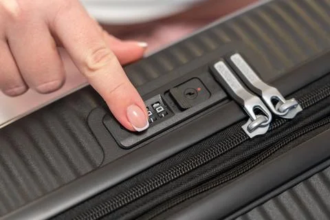 Fingering the numbers on the combination lock of the suitcase to open it Stock Photos