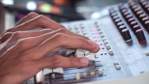 Fingers adjusting mixing board controls, sound engineering equipment, Stockbeeldmateriaal 344011463