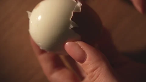 Fingers carefully peel shell from boiled brown egg on table Stock Footage 312767192