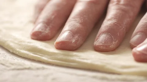 Fingers dusted with flour press the perimeter of pizza dough. Stock Footage 270534906