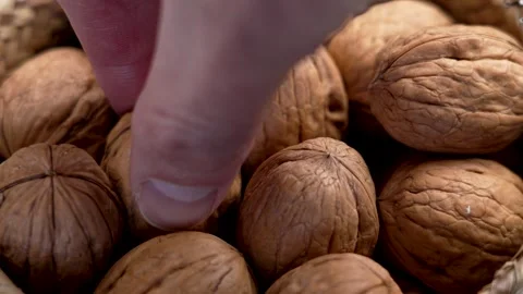 Fingers of hand taking walnut from rustic wicker basket. Stock Footage 302816859