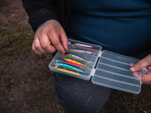 Fingers hover over the lure selection. Carefully selecting the size and color of Stock Photos