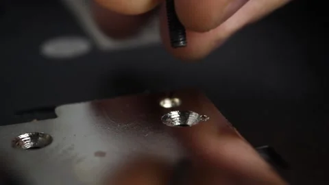 Fingers insert a screw into the hole and a screwdriver twists it, closeup Stock Footage 132194830