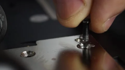 Fingers insert a screw into the hole, a screwdriver tightens the screw Stock Footage 132194860