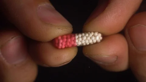 Fingers open the capsule with pellets Stock Footage 127620418