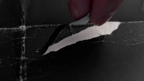 Fingers peeling a torn layer of black paper Stock Footage 302108372