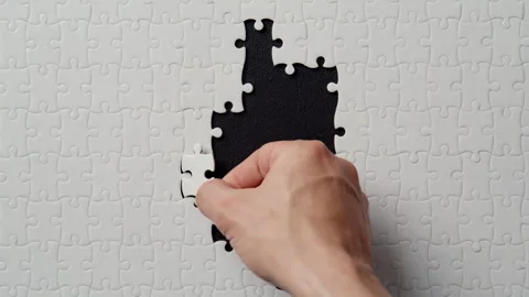 Fingers placing jigsaw segment completing puzzle structure on black closeup Stock Footage 332309121