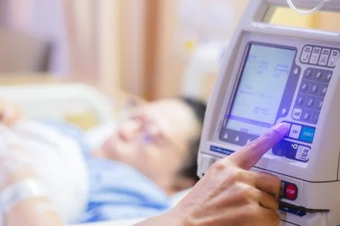 Fingers press control panel for adjust Infusion pumps with blurry patient in  Stock Photos