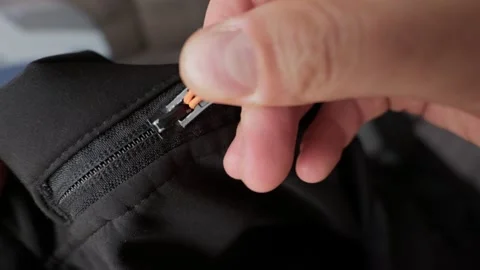 Fingers Pulling Orange Cord Zipper on Black Outdoor Jacket Detail Video stock 338092973