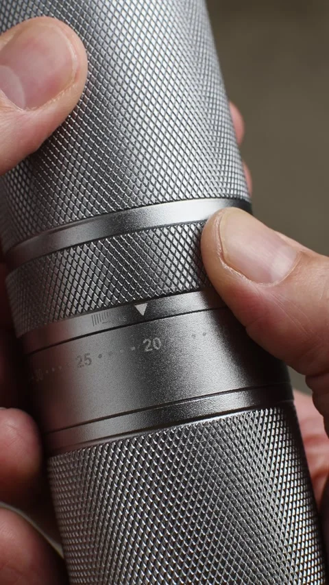 Fingers rotate the numbered grind ring on a metal manual coffee grinder in a Stock Footage 346743617