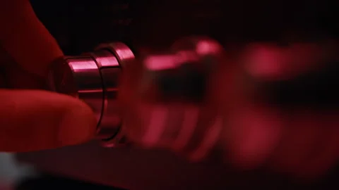 Fingers rotating volume knob at dark room closeup. Macro man adjusting sound Stockbeeldmateriaal 332665907