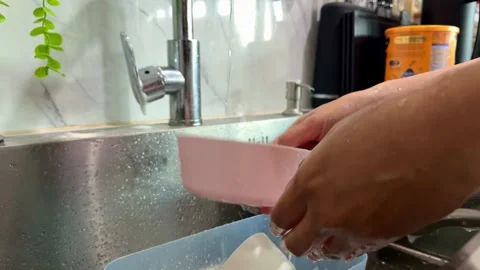 Fingers scrubbing kitchenware under faucet, dishwashing routine, cleaning and Stock Footage 345289619