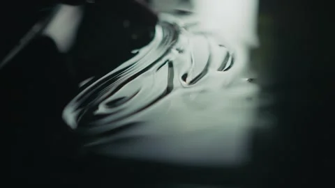 Fingers Skillfully Creating Intricate Patterns on a Fluid Surface with Grace and Stock Footage 309474230