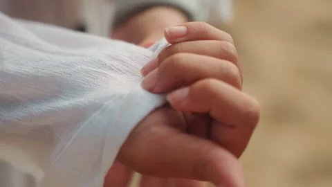 Fingers smoothing fabric as setting sun illuminates shoreline scene. Individual Видео 345168187